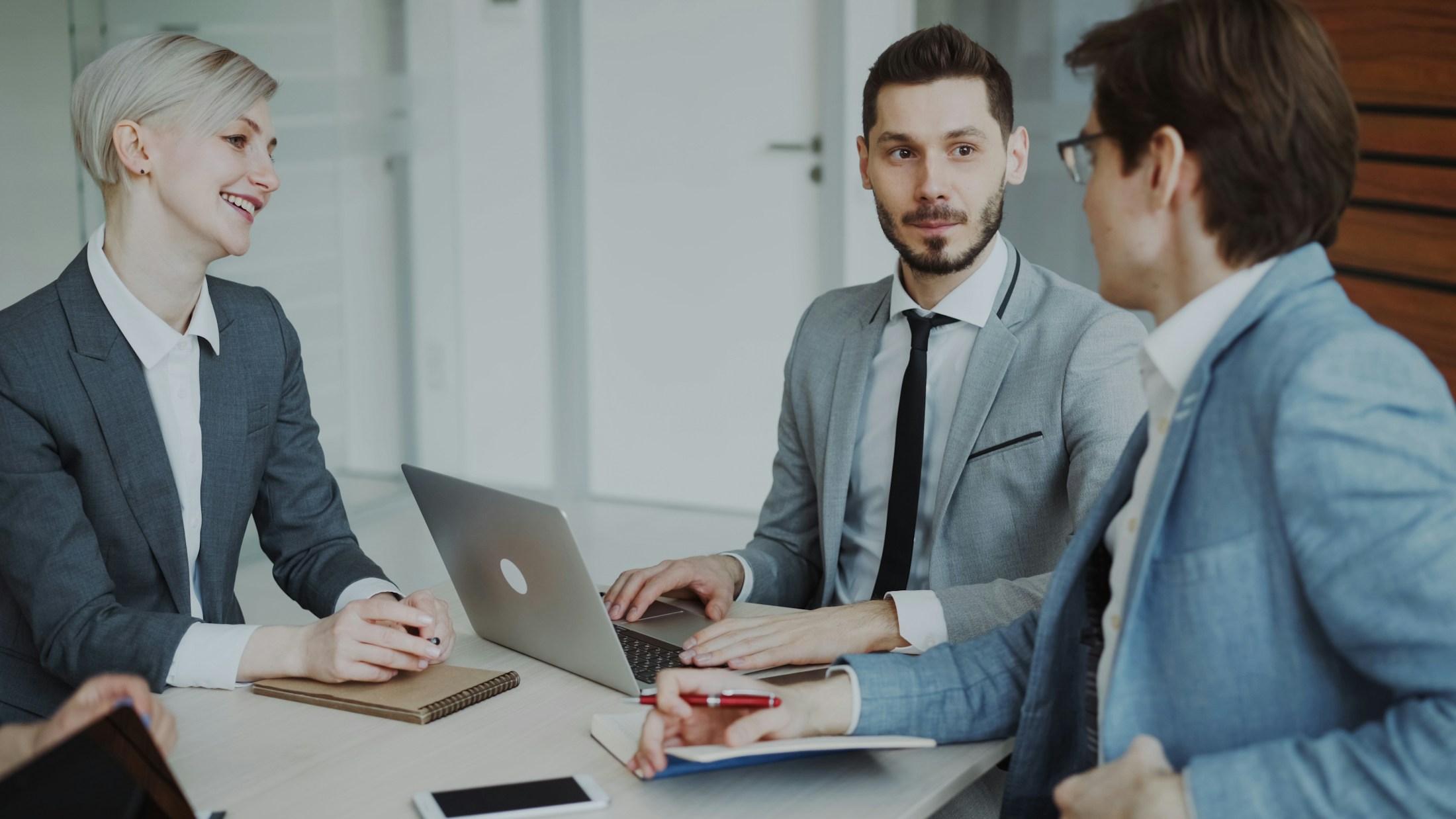 Three professionals discussing a business matter around a laptop