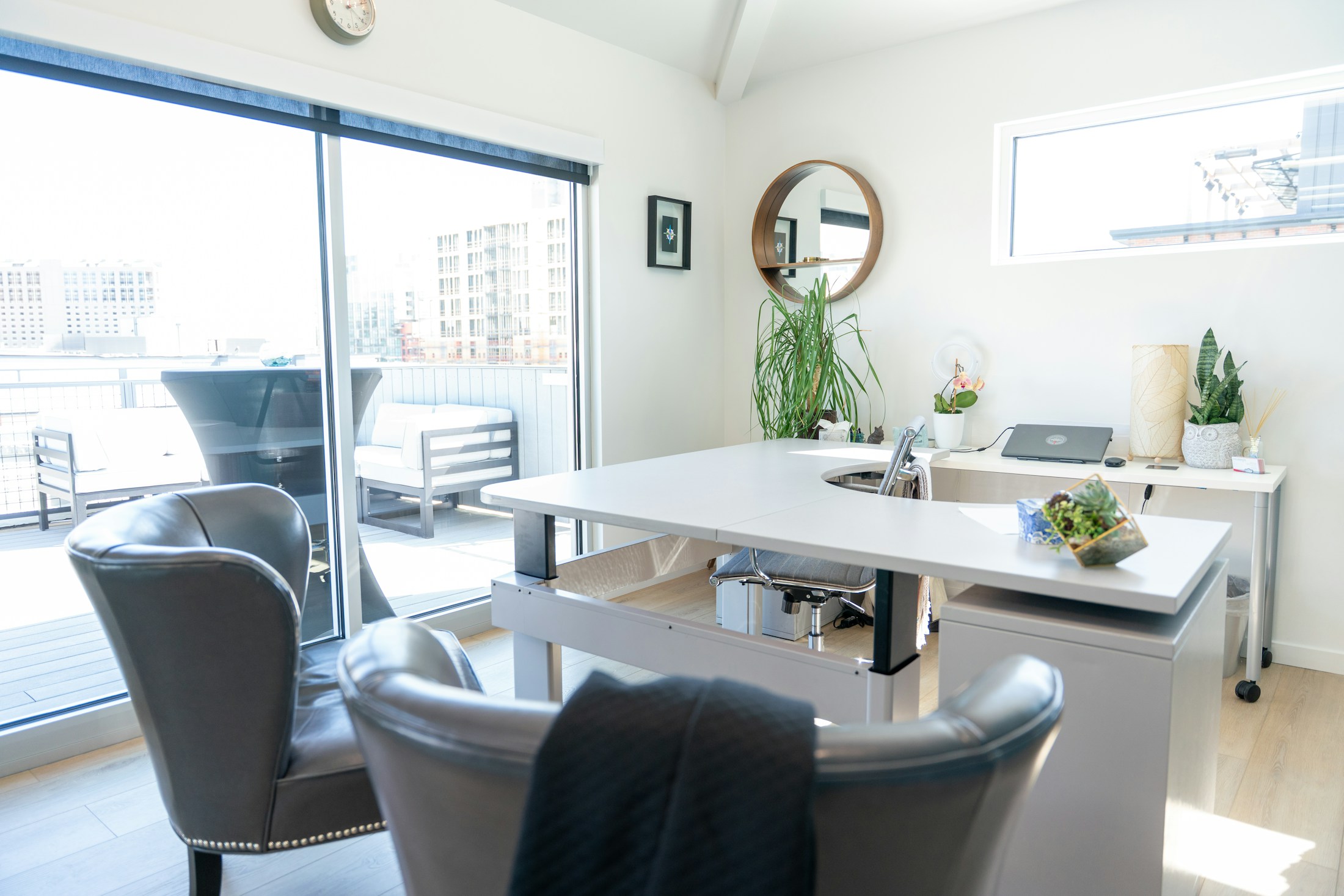 A bright executive office with a white desk and visitor chairs