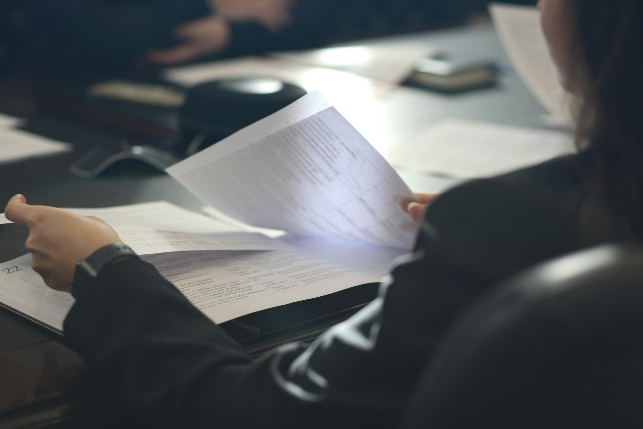 A professional carefully reading papers at a meeting table