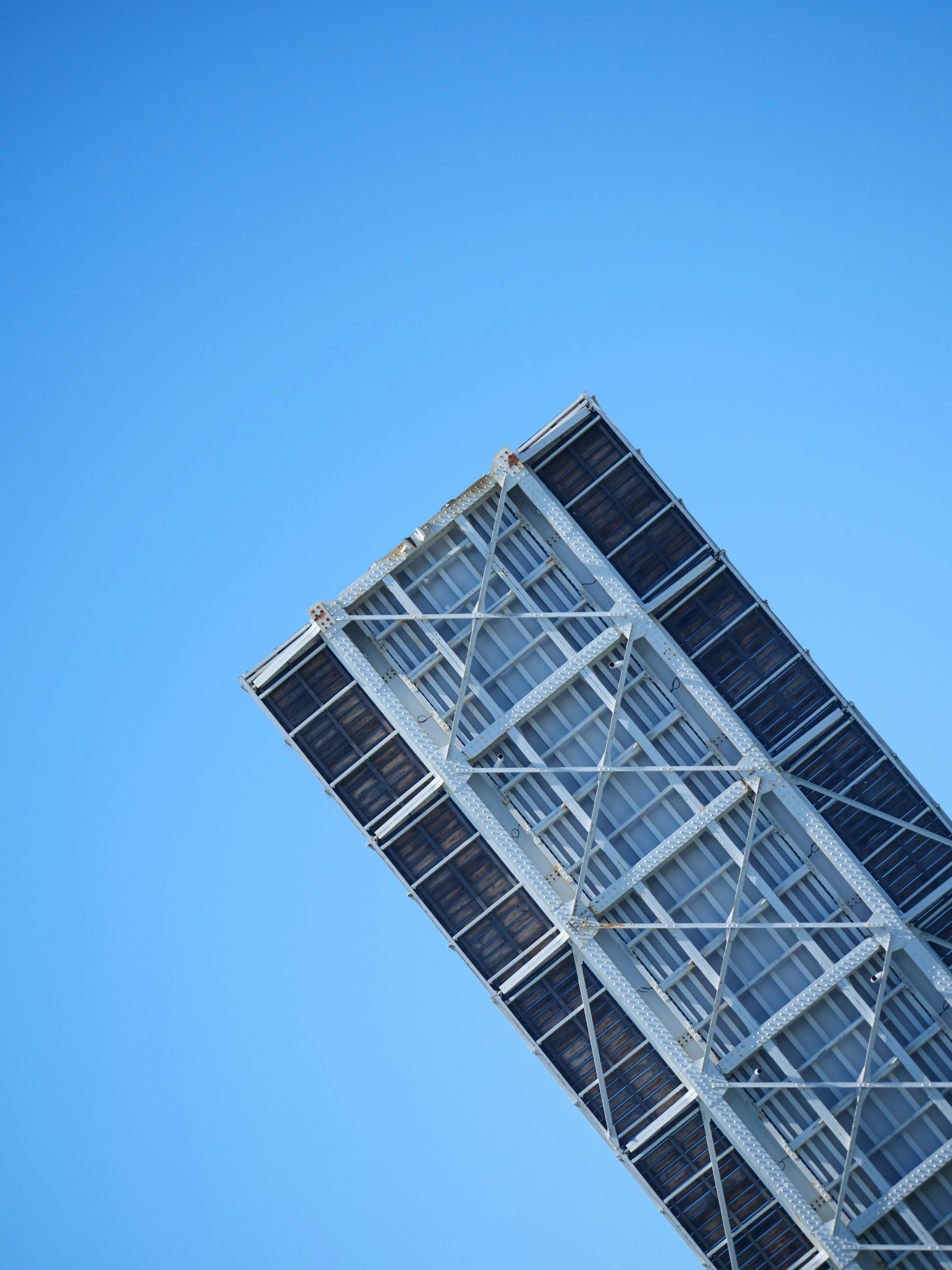 Geometric steel framework beneath panels against a clear blue sky
