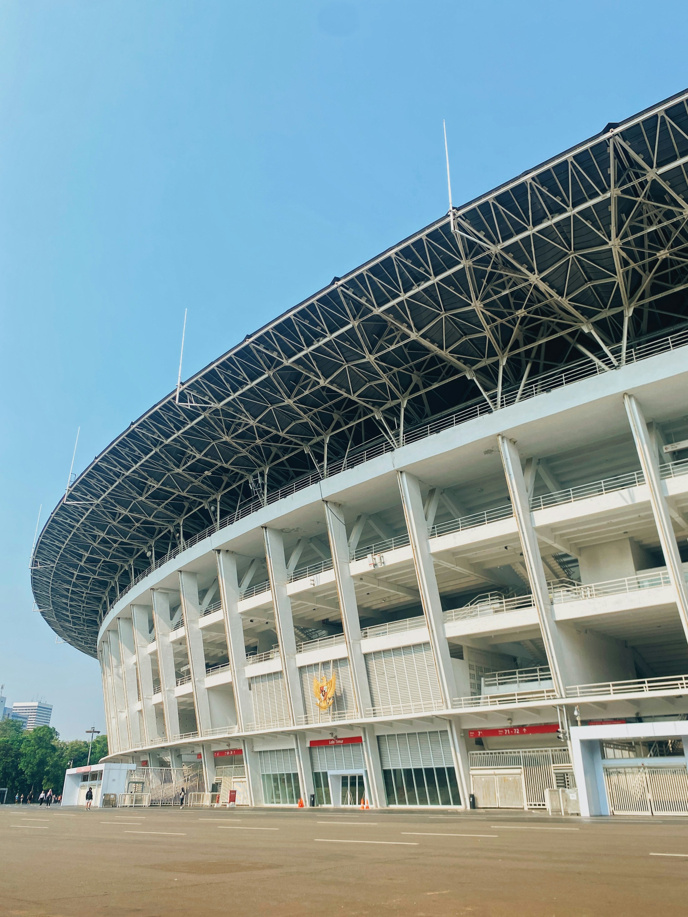 The facade of Gelora Bung Karno Stadium beneath a clear blue sky
