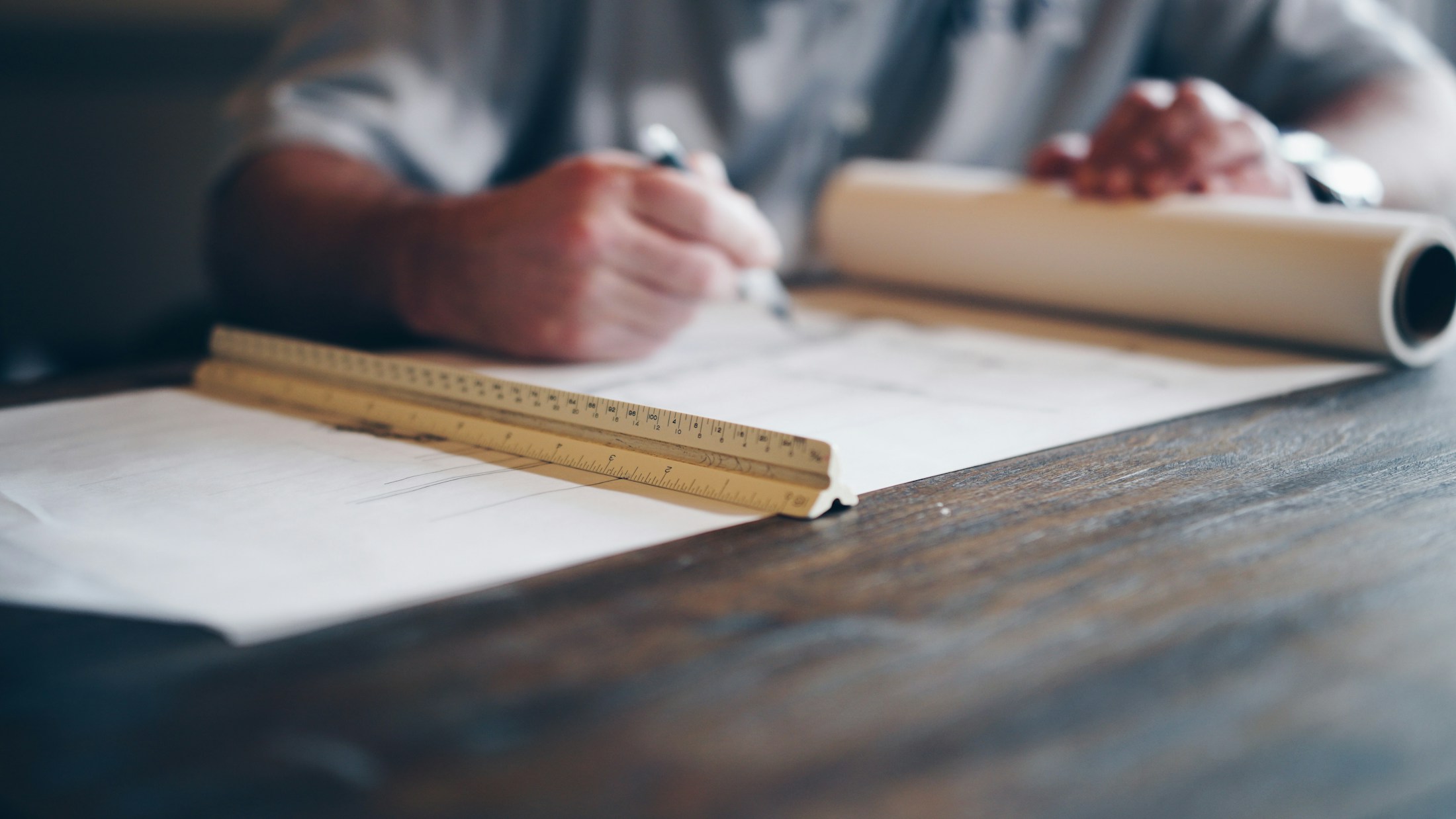 A person drafting a plan with a ruler and drawing tools